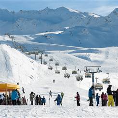 Skifahrer auf Skipiste mit Sessellift im Hintergrund
