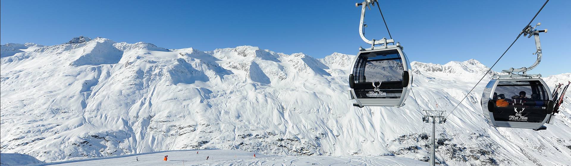Gondolas in front of a snow-covered mountain landscape