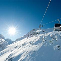 Gondola in front of a mountain landscape in winter with bright sunshine