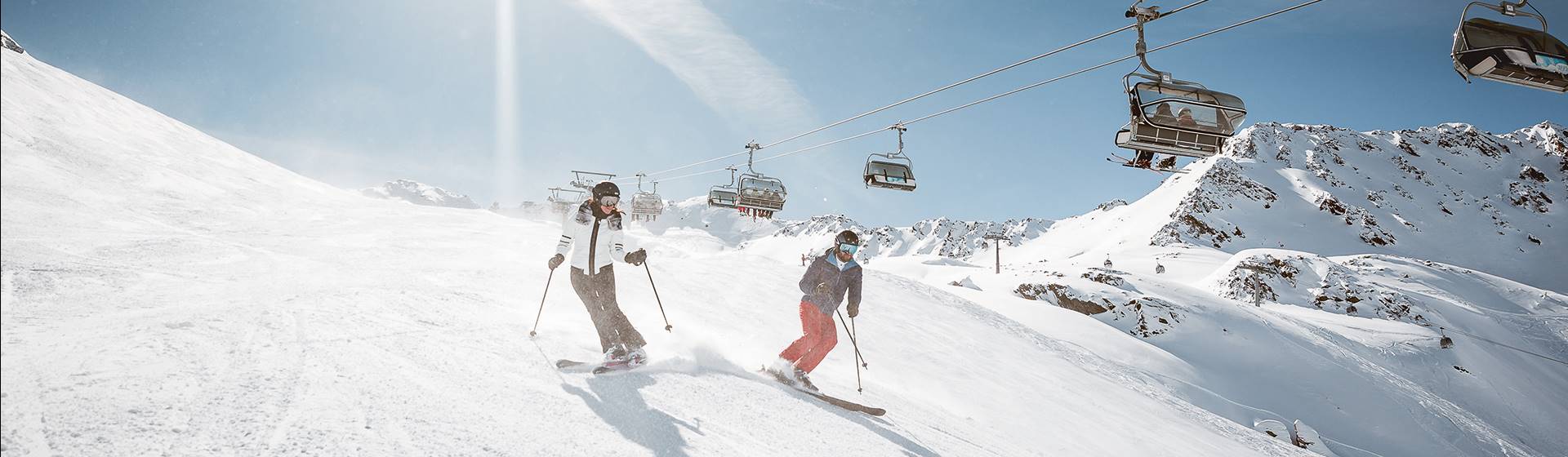 Zwei Skifahrer auf Skipiste unter Sessellift