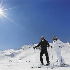 Couple in ski outfit on ski slope in bright sunshine